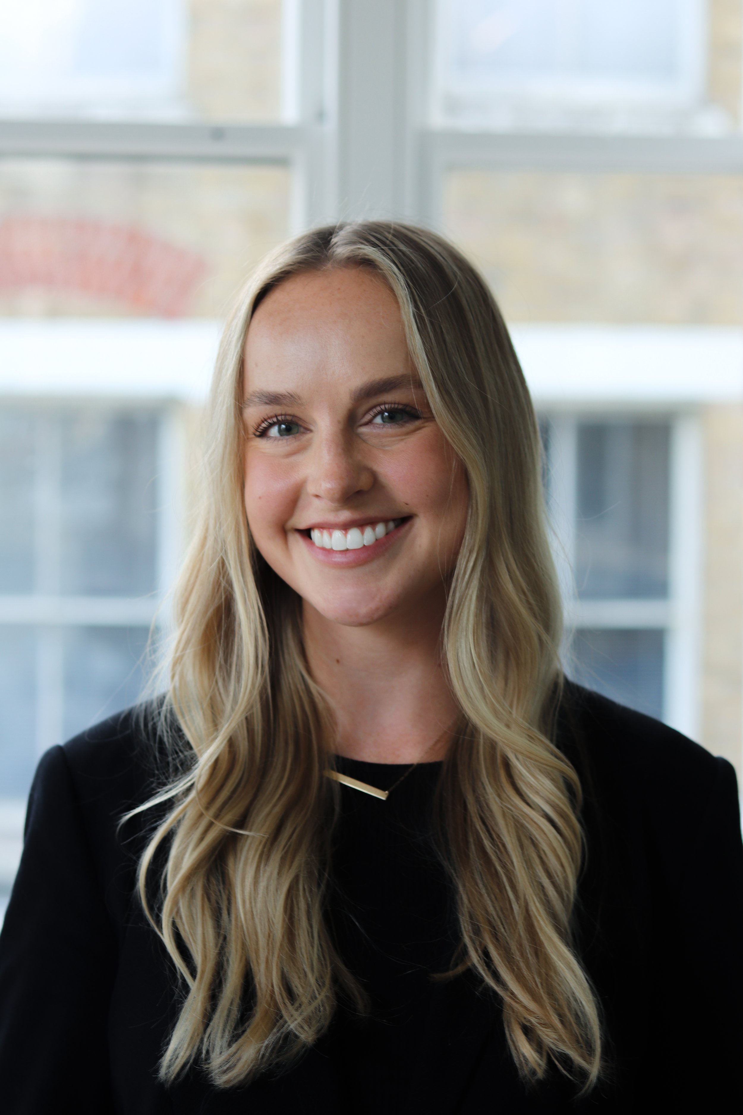 Portrait of Nicole Cadden smiling, in front of a bright window