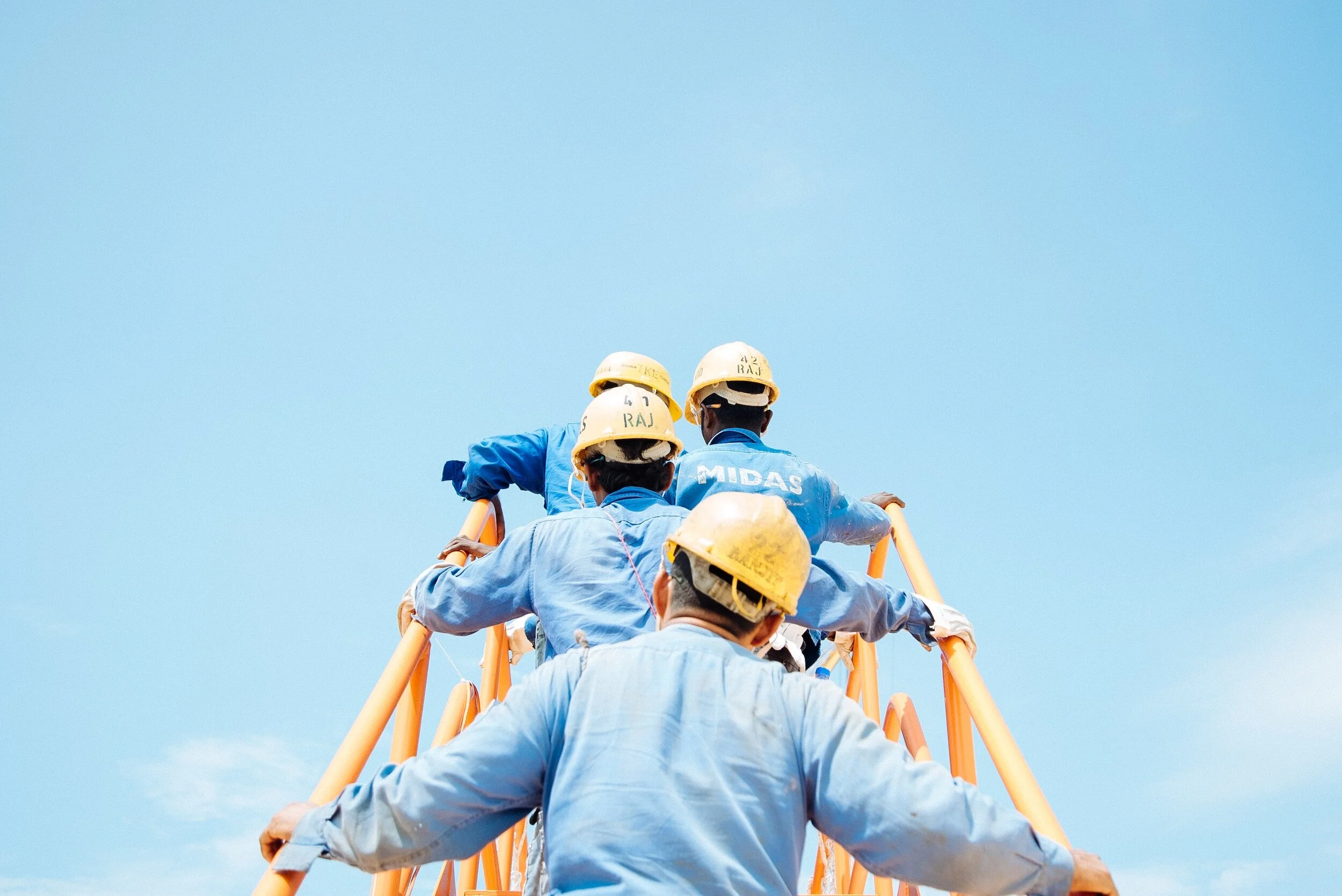 Workers in blue uniforms and yellow hard hats photographed from below — Skills Connect case study