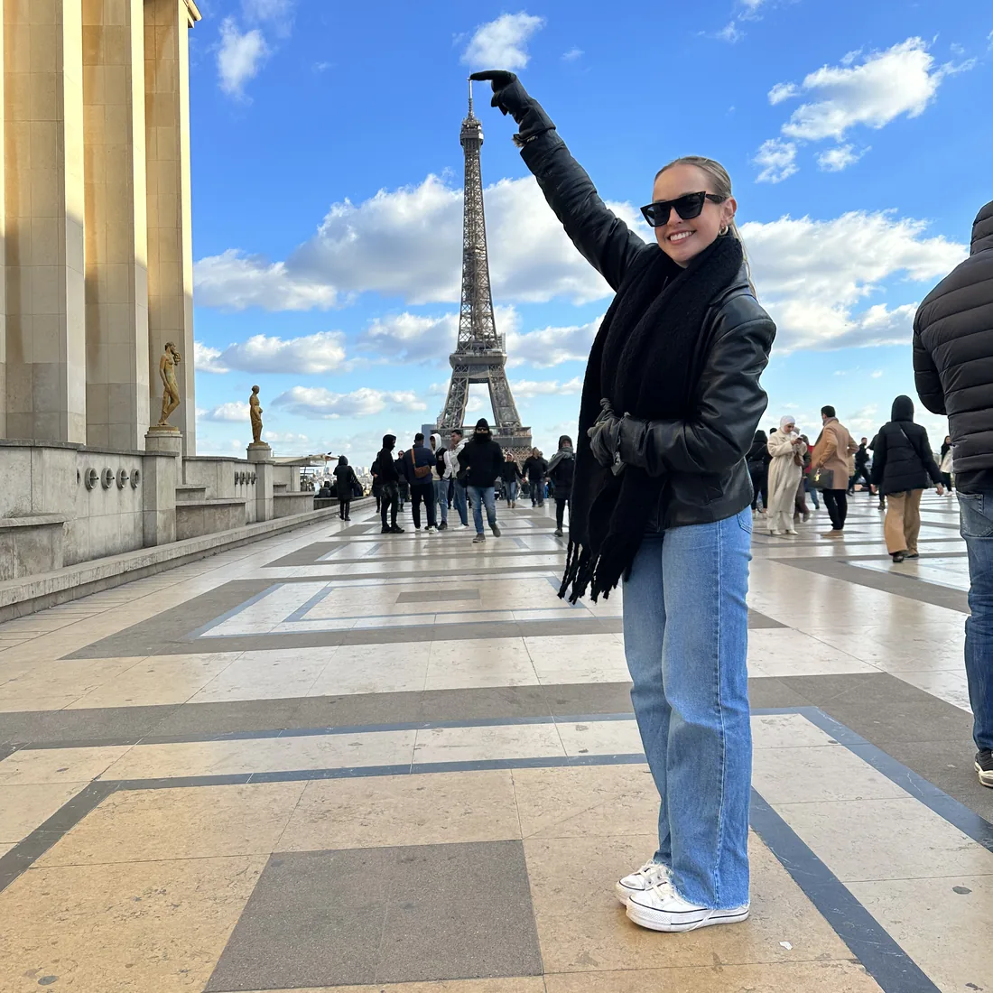 Nicole on the Trocadero esplanade in Paris, arm raised, pointing back at the Eiffel Tower