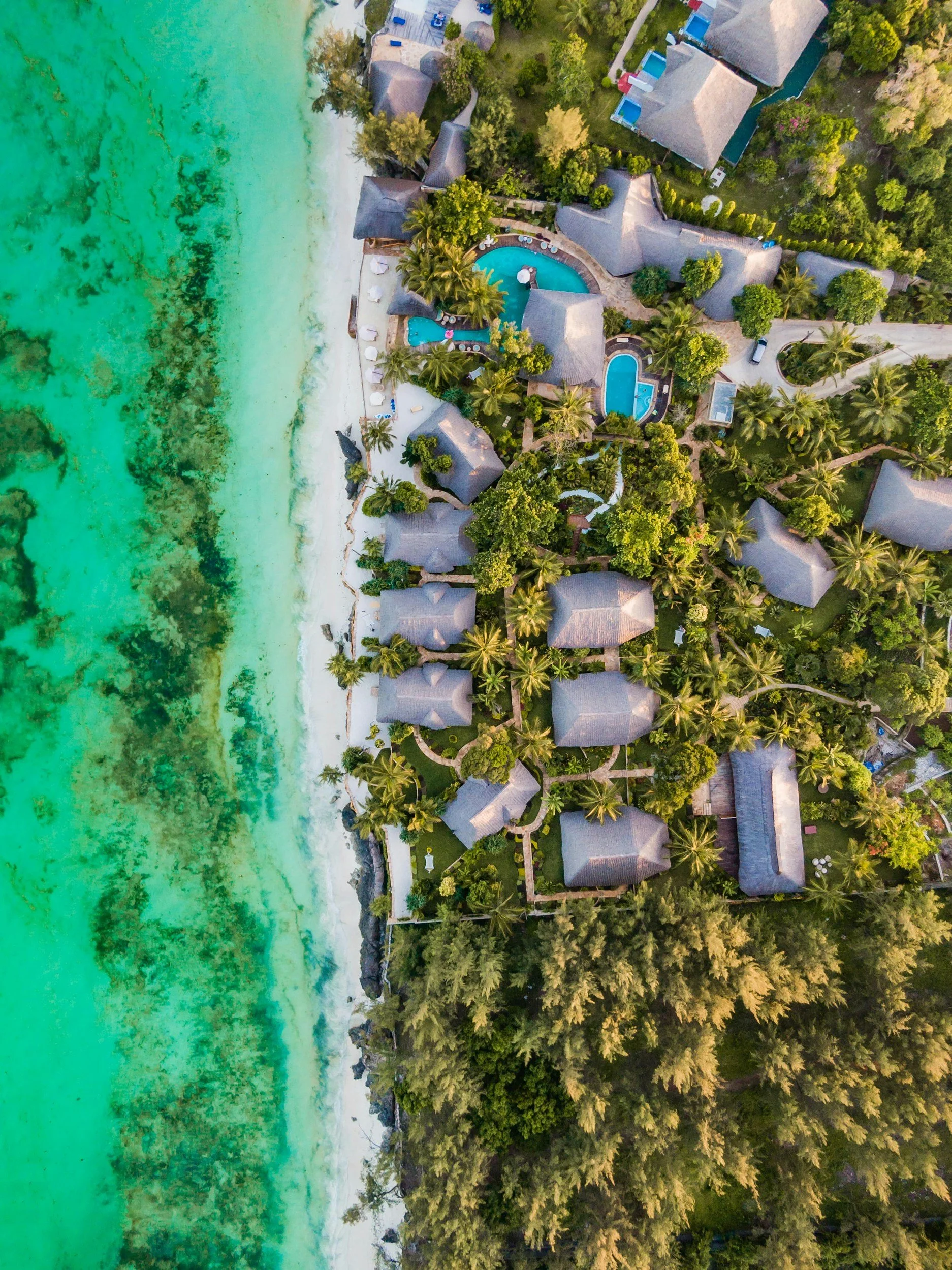 Aerial view of thatched resort villas beside a turquoise shoreline — Luxury Bound case study